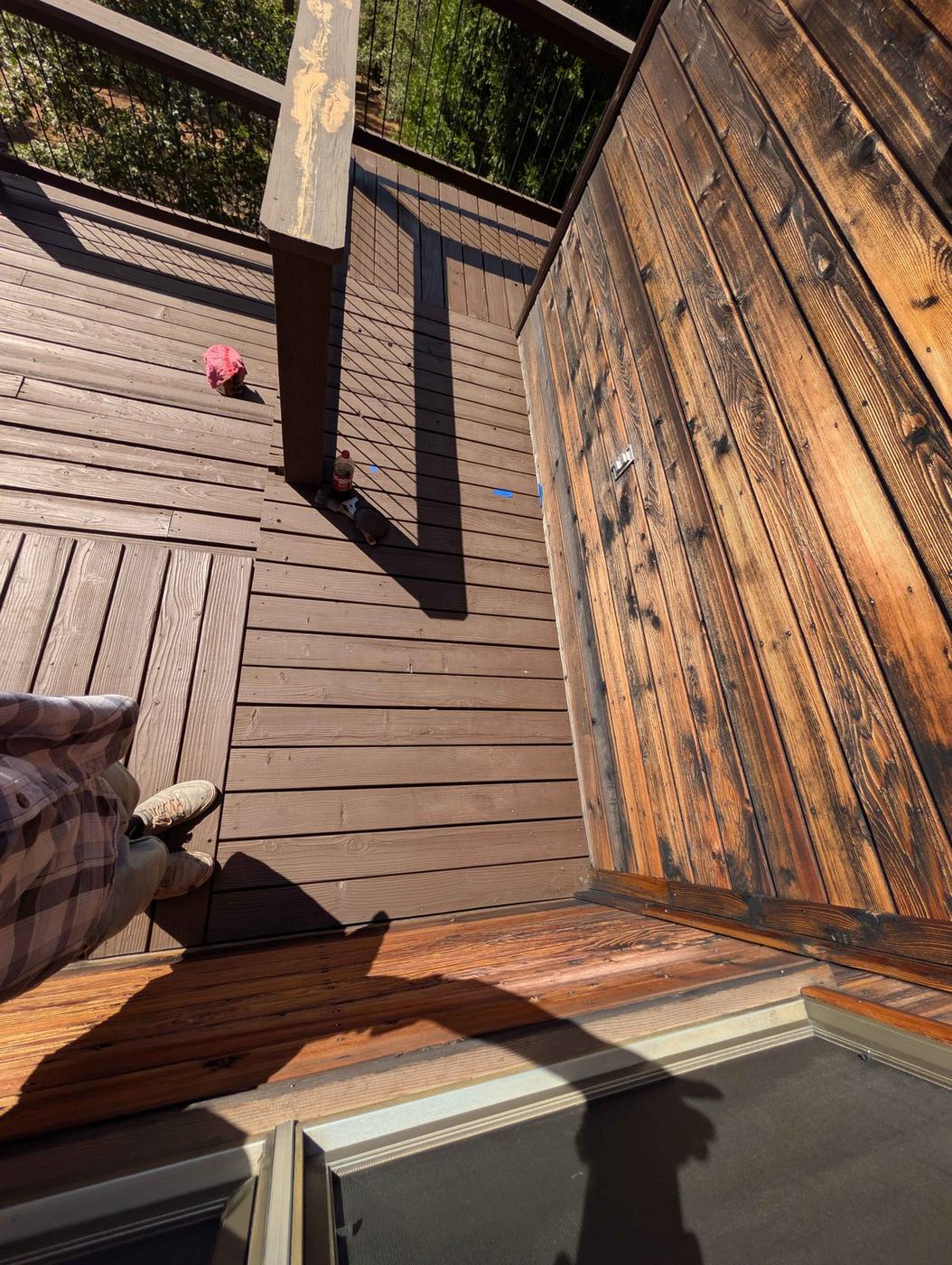 A deck part way through staining, fresh colour beside weathered boards