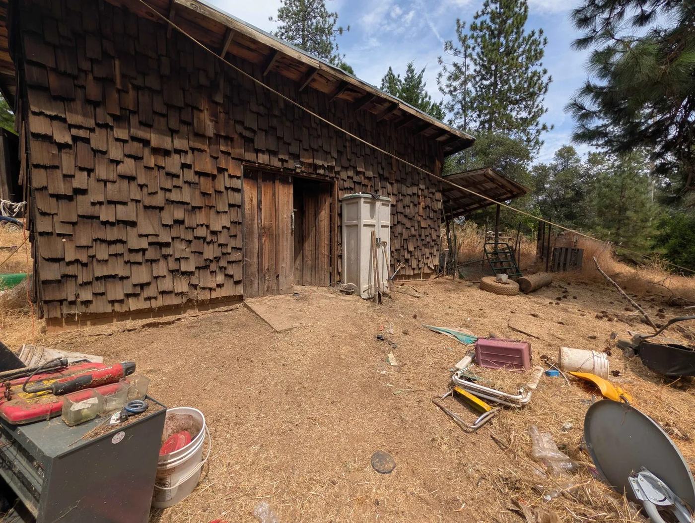 Old equipment and junk stored around an outbuilding